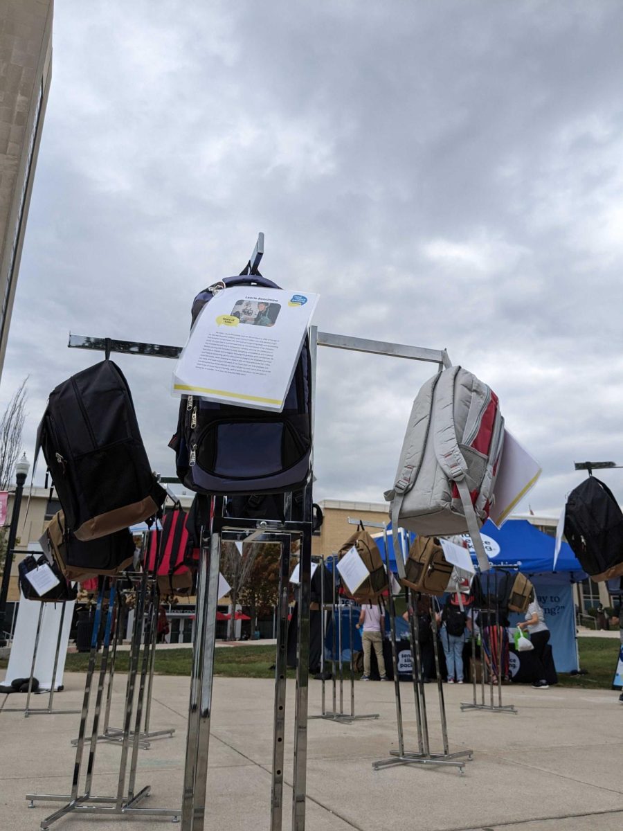 Stuffed backpacks hanging on clothing racks with stories attached to the backpacks about students who died by suicide as a part of Sending Silence Packing on Wednesday in MLK Commons. (Nyla Owens | Northern Star)