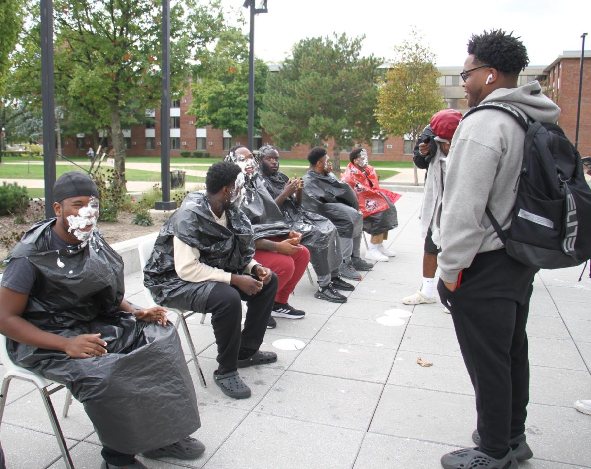Black Male Initiative members laugh with a crowd of students after getting pied in the face on Thursday during the Pie BMI event hosted near the MLK Commons. (Ariyonna McGahee | Northern Star)