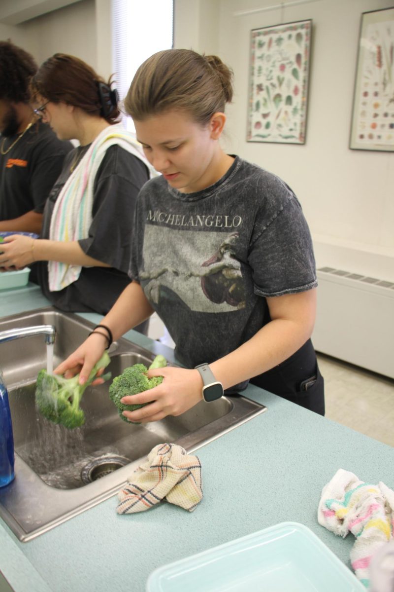 Christina Annerino, a senior double majoring in nursing and sociology, washes broccoli before placing it on a cutting board. Students had the option to either have fresh broccoli or fresh lettuce and cabbage greens from the Anderson Market Garden. (Nyla Owens | Northern Star)
