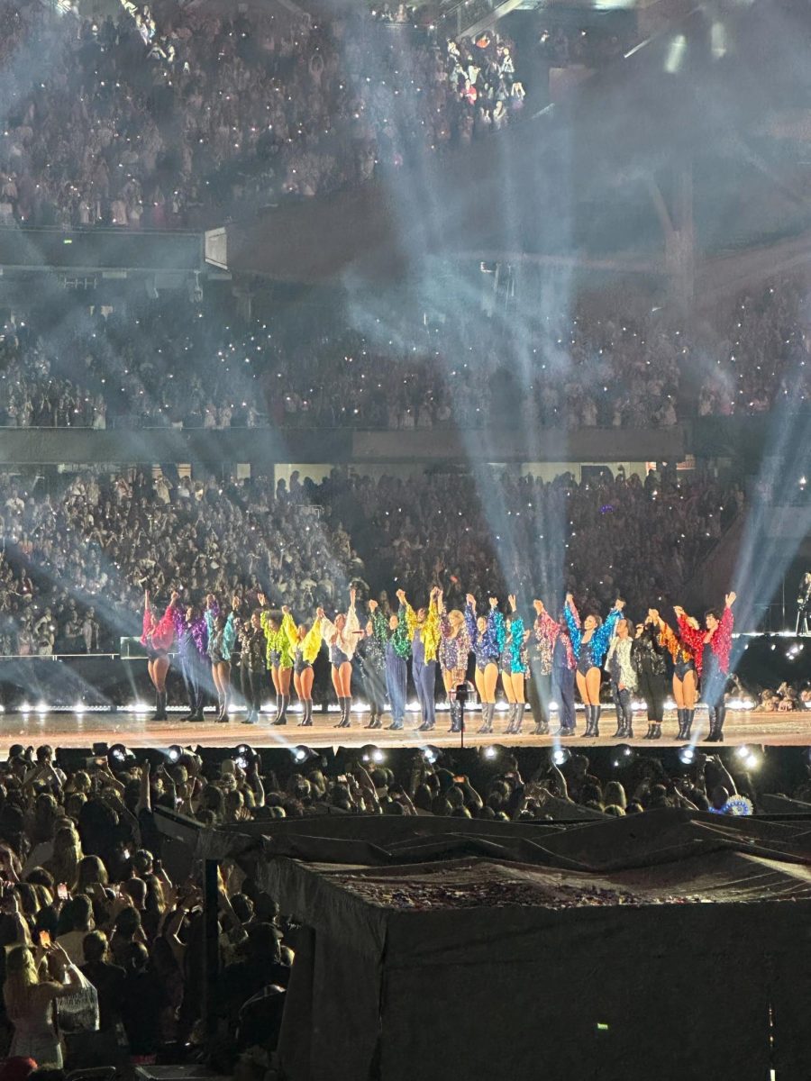 Taylor Swift and her dancers raise their hands during the final bow at one of her concerts. Swift has recently released a concert film of her Era’s Tour in theaters. (Tamya Burch | Northern Star)