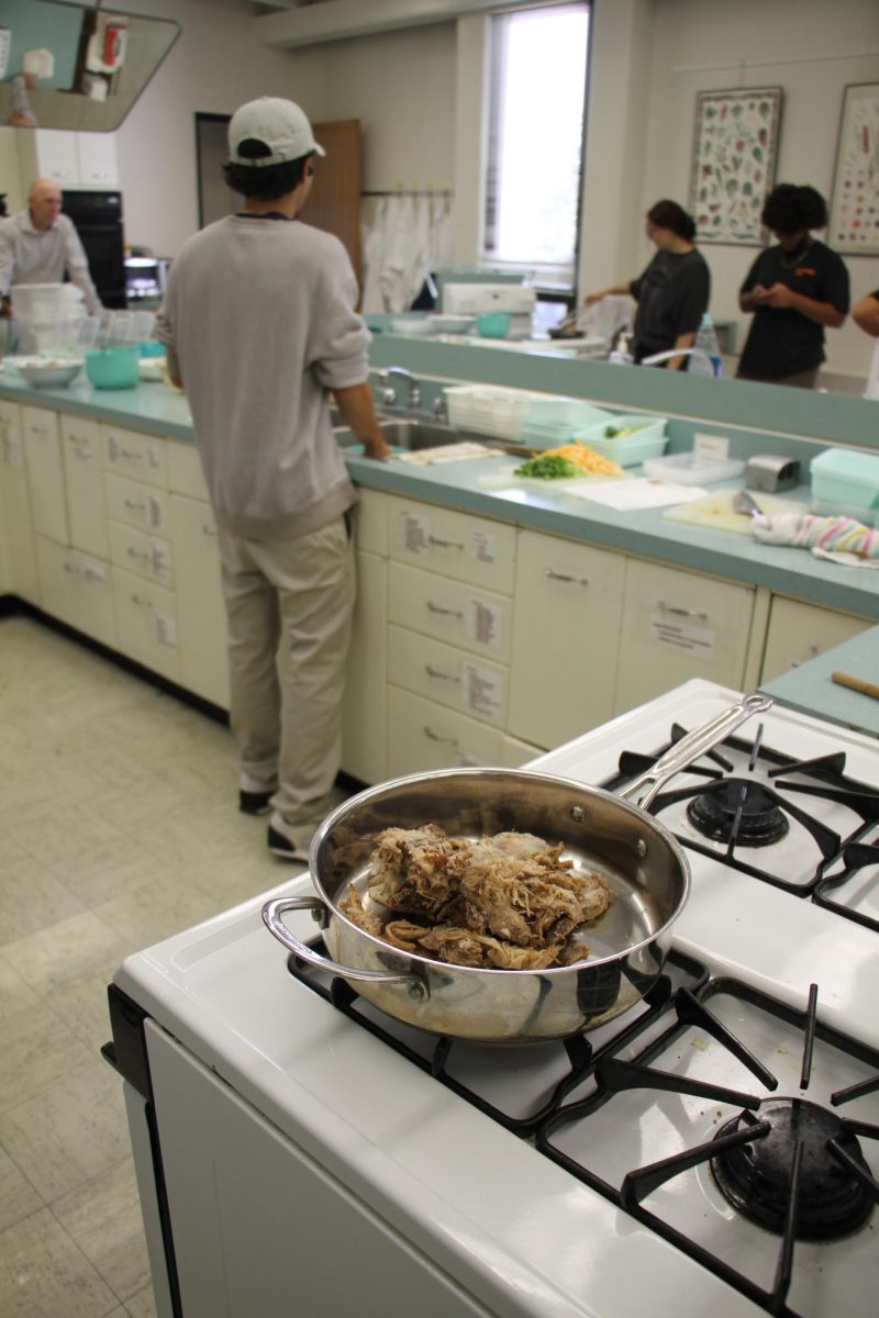 A+pan+of+precooked+pulled+pork+sits+on+a+low+simmer+to+slowly+reheat+the+pork+to+load+the+potatoes.+The+Edible+Campus+Meal+Prep+program+allows+students+to+develop+useful+life+skills.+%28Nyla+Owens+%7C+Northern+Star%29%0A