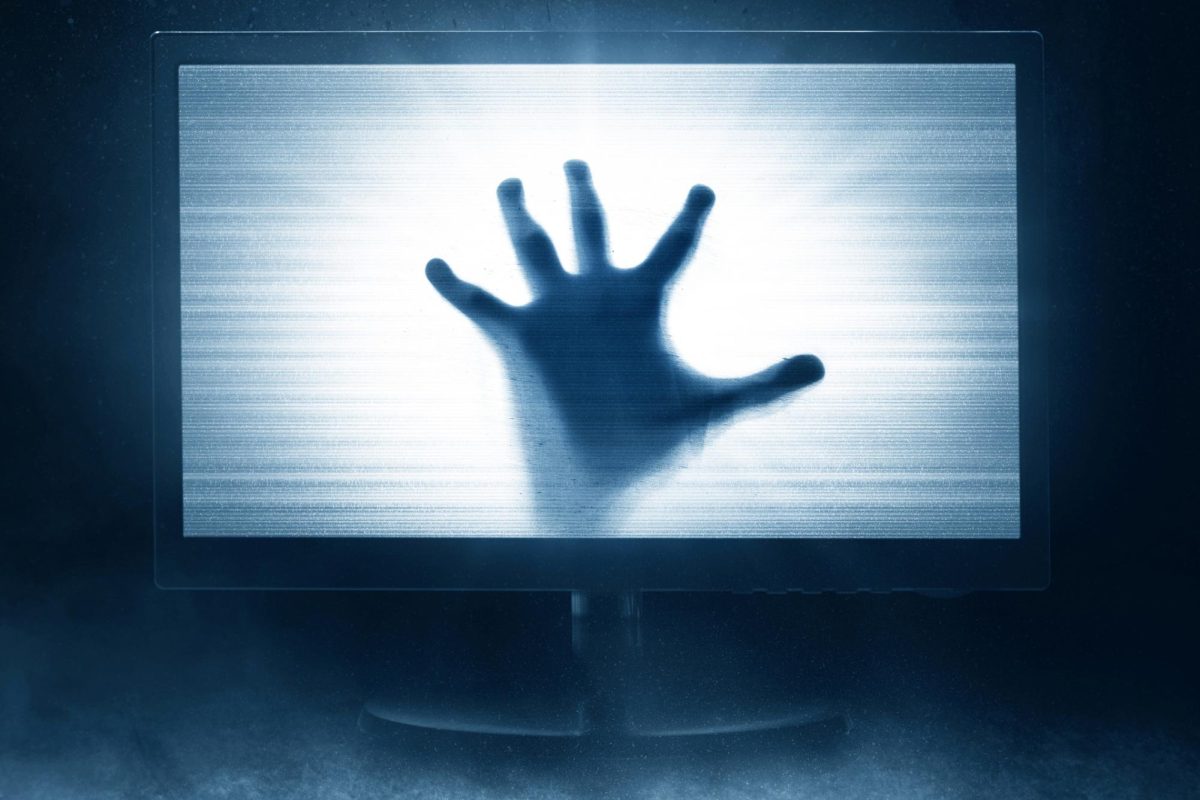 A persons hand presses up through the inside of a computer screen. 2023 has produced numerous horror films, and some were loved while others were hated by fans. (Courtesy of Getty Images)