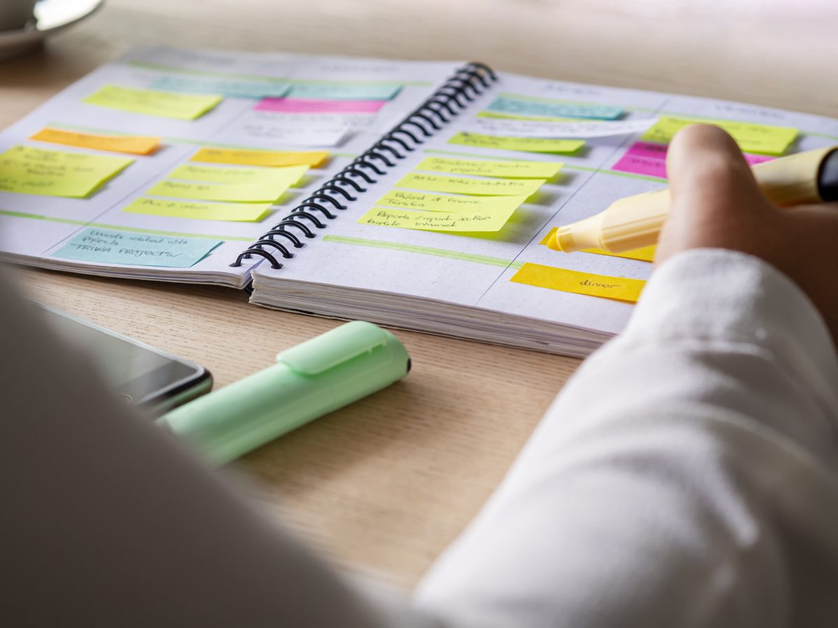 A person holds a yellow highlighter over an agenda covered in colorful sticky notes. Now that were halfway through the semester, developing efficient study techniques is crucial. (Courtesy of Getty Images)