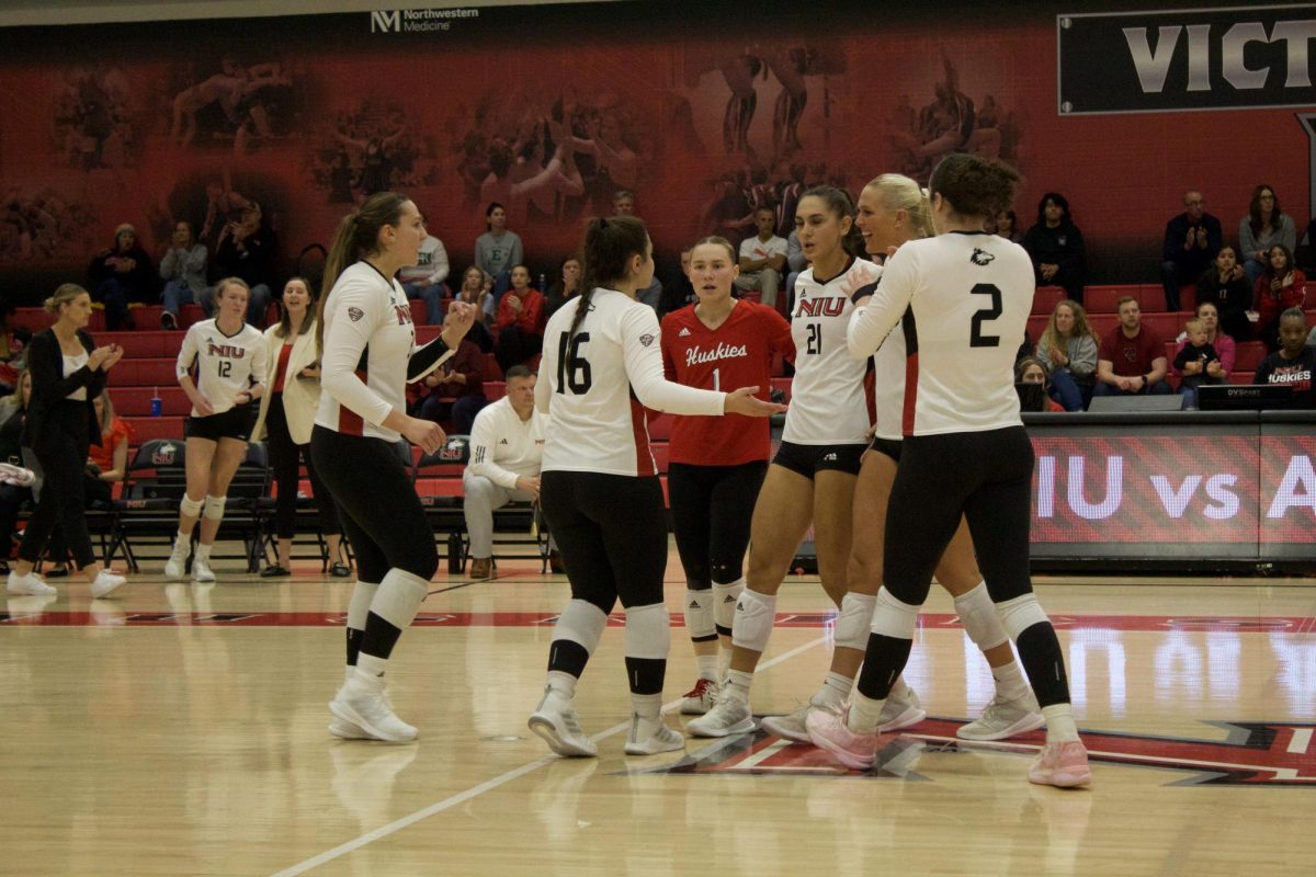 From left: Graduate student outside hitter Katie Erdmann, junior setter Sophie Hurt, junior libero Crew Hoffmeier, junior outside hitter Nikolette Nedic, sophomore middle blocker Savanah Brandt and graduate student outside hitter Isabelle Percoco gather into a huddle during NIUs Oct. 13 matchup with the Eastern Michigan University Eagles at Victor E. Court. The Huskies suffered their second consecutive sweep in Fridays series-opener against Central Michigan University. (Skyler Kisellus | Northern Star)