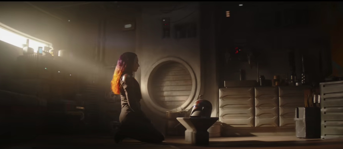 Natasha Liu Bordizzo as Sabine Wren kneels, facing a Mandalorian helmet in Ahsoka. Season 1 of the series can be streamed on Disney+. (Courtesy of YouTube)