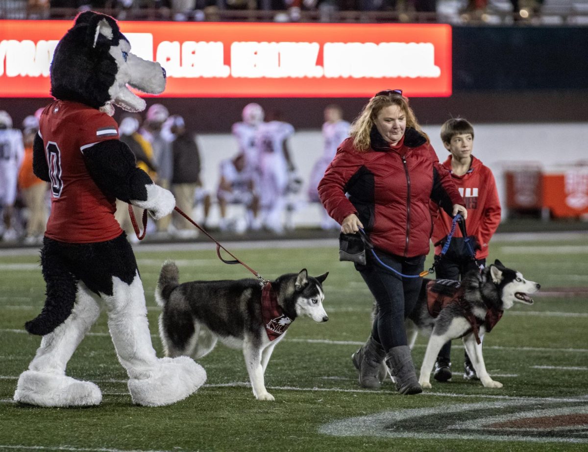 Victor E. Huskie walks Mission II onto the Huskie Stadium football field alongside Lisa Boland, coordinator for the mascot program, with Mission III. Mission II officially retired as NIUs live mascot at the NIU football game against Western Michigan University on Nov. 14. (Tim Dodge | Northern Star)