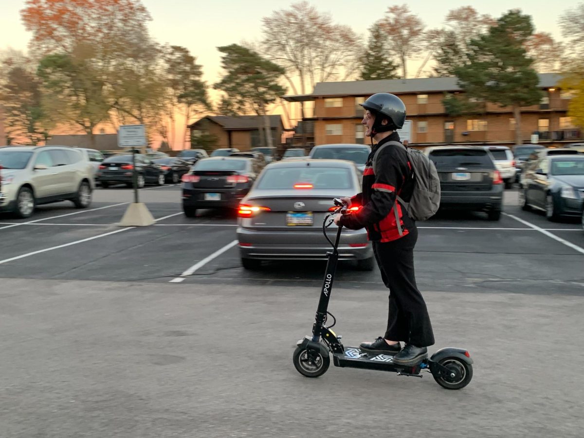 Jay Jarvis, program assistant for transfer programming, takes off on their Apollo electric scooter outside the Peter Campus Life Building. NIU students and faculty are using e-vehicles to travel around campus. (Rachel Cormier | Northern Star)