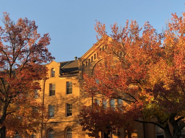 The setting sun covers Williston Hall in an orange glow with colored trees in front. The sun sets now at 4:30 p.m., marking the return of winter. (Josephine Dunmore | Northern Star) 