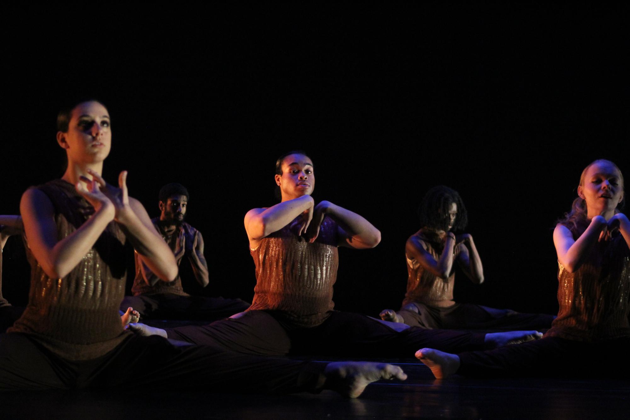 Dancers showcase strong emotions as they sit in a split position while performing “ROOT: Mwanza wa mwili ni roho”  on Wednesday. Admission is free for NIU students, with tickets available for purchase online for residents and NIU faculty. (Sasha Norman | Northern Star)
