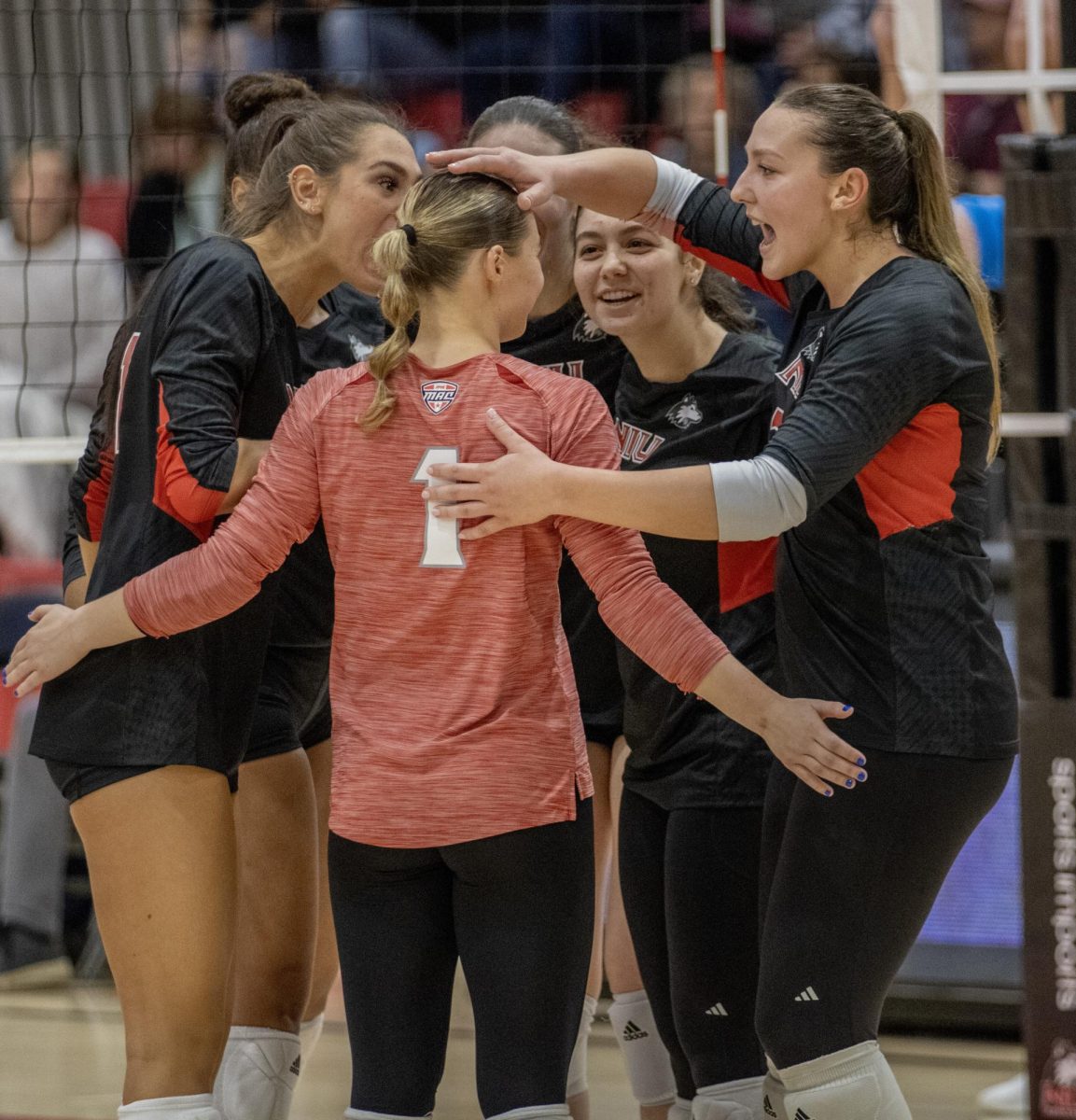 NIU volleyball players huddle together during Friday’s match against the University of Akron. (Tim Dodge | Northern Star) 