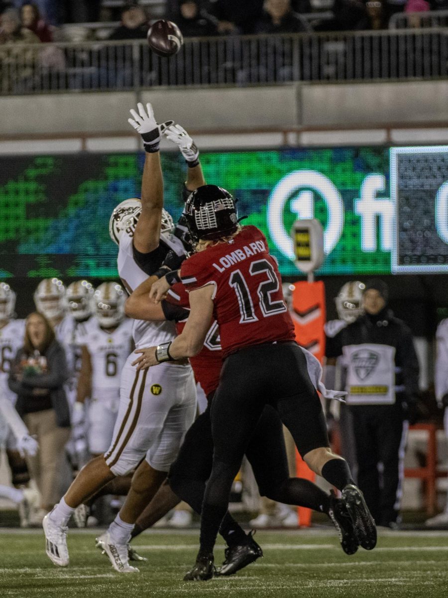  Redshirt senior quarterback Rocky Lombardi (12) throws the ball downfield with a Western Michigan defender attempting to block the pass. NIU shut out the Broncos 24-0 during the final home game of the season. (Tim Dodge | Northern Star)

