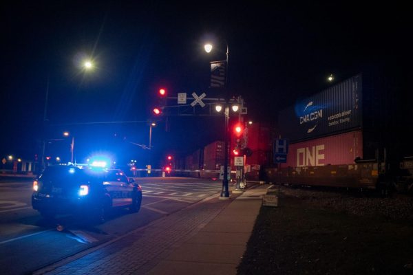 A police car flashes its light at the intersection of Fourth Street and Lincoln Highway. A train stopped downtown, closing major intersections for two hours on Sunday. (Sean Reed | Northern Star)