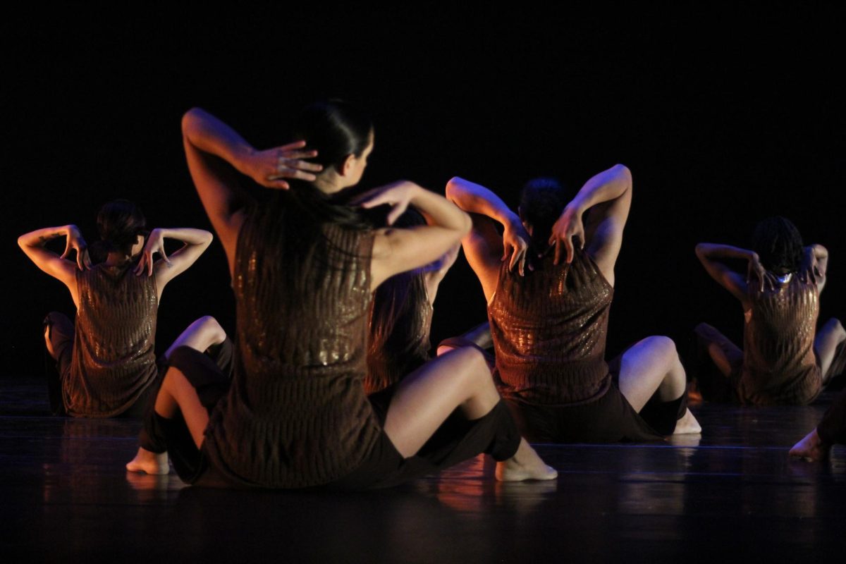 A+group+of+dancers+sit+together+with+their+hands+on+their+shoulders.+NIUs+School+of+Theatre+and+Dance+will+perform+its+2023+Fall+Dance+Concert+from+Nov.+30+to+Dec.+3.+%28Sasha+Norman+%7C+Northern+Star%29