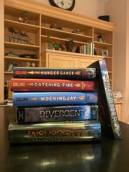 Six books stacked on top of each other sit on a black table. An interest in dystopian books may be reemerging since the new Hunger Games film was released. (Brynn Krug | Northern Star)
