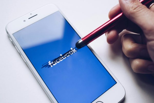 A hand scratches out the Facebook logo on a smartphone with a digital pen. Senior Opinion Columnist Emily Beebe believes social media platforms infringe on the freedom of speech when they limit what users can post. (Thought Catalog | Pexels)