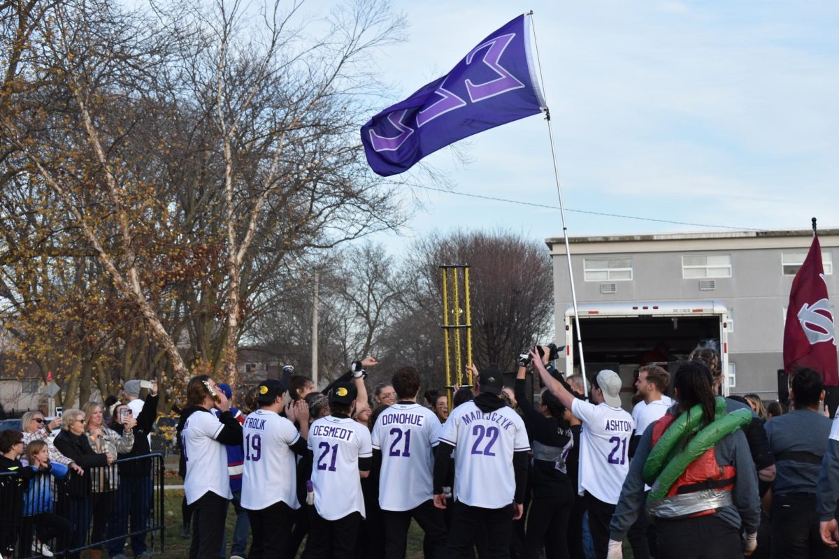 Jay+Mueller%2C+Tri+Sigs+coach+and+member+of+Phi+Sigma+Kappa%2C+hoists+the+Sigma+Sigma+Sigma+flag+while+Tri+Sigs+members+hold+up+their+first+place+trophy.+Sigma+Sigma+Sigma+won+the+Tugs+tournament+Saturday%2C+increasing+its+win+streak+to+three+years+in+a+row.+%28Nick+Glover+%7C+Northern+Star%29
