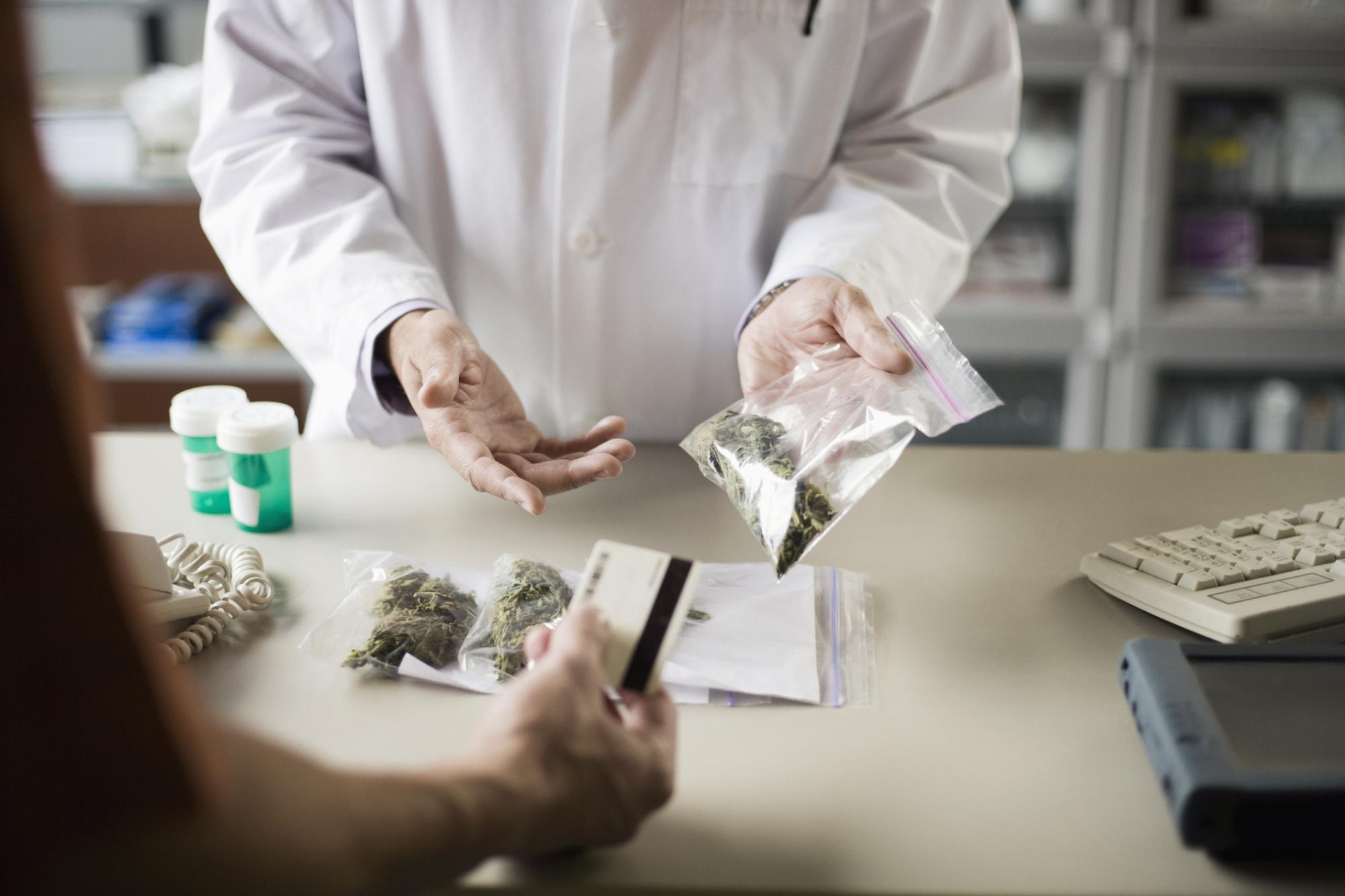 A person hands a card to a person in a lab coat holding a plastic bag. Senior Opinion Columnist Emily Beebe believes a marijuana dispensary is a good addition to DeKalb. (Juniperimages | Getty Images)