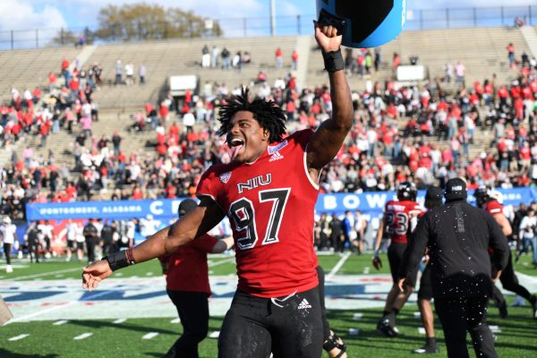 Sophomore defensive end Roy Williams holds a cooler high after dumping Gatorade on NIU football head coach Thomas Hammock. The Huskies defeated Arkansas State University 21-19 in the Camellia Bowl on Saturday. (Todd Thompson | Courtesy of NIU Athletics)