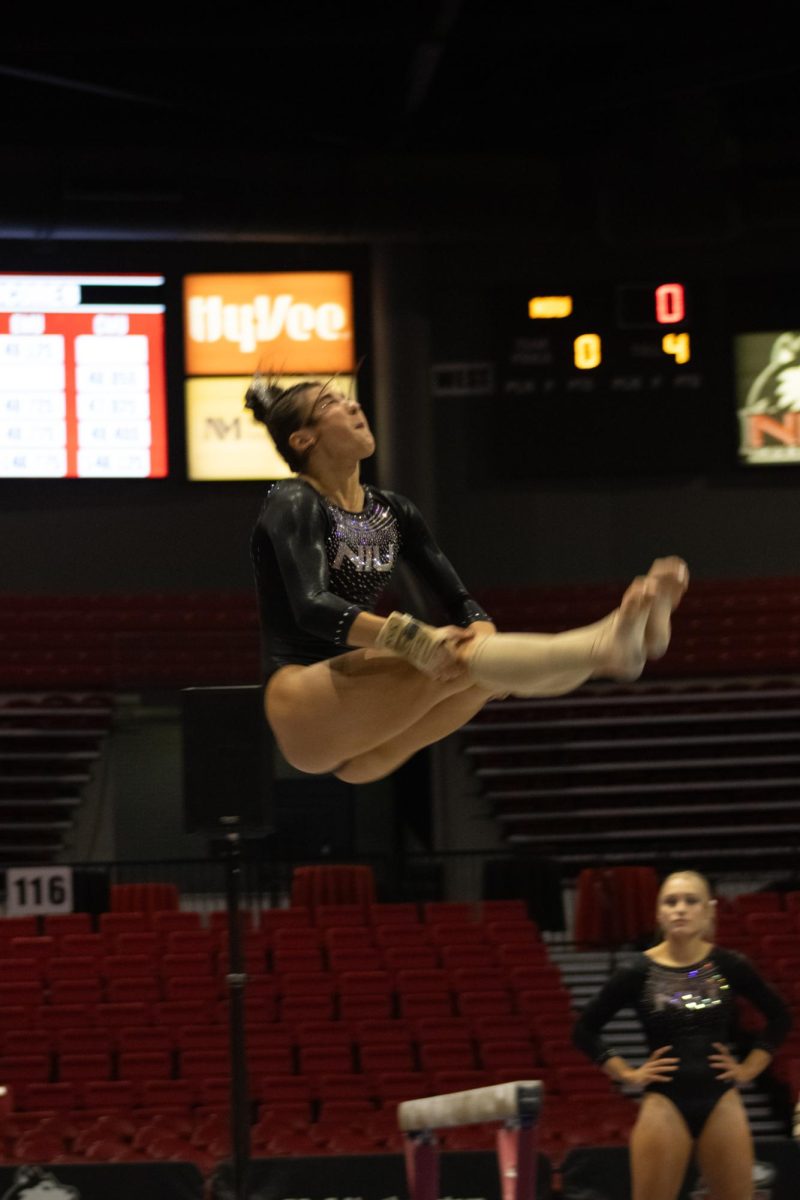 Junior gymnast Isabella Sissi holds the underneath of her legs as she flips backward mid-air. Sissi scored 39.050 all-around for the meet. (Sean Reed | Northern Star)