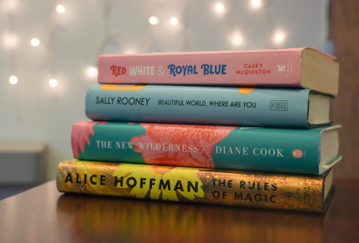 A stack of four romance and fantasy books sit on a table with lights in the background. Many books are coming out next year, including books similar to the books stacked here. (Anna Scanlan | Northern Star)