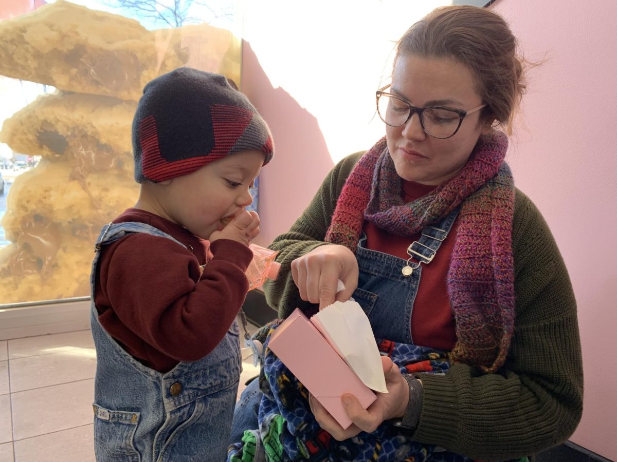 Stephanie Meyn, a Cortland resident, shares a Crumbl chocolate chip cookie with her 17-month-old son Zachary. Meyn received a free chocolate chip cookie for having the store’s mobile app downloaded at the grand opening. (Rachel Cormier | Northern Star)