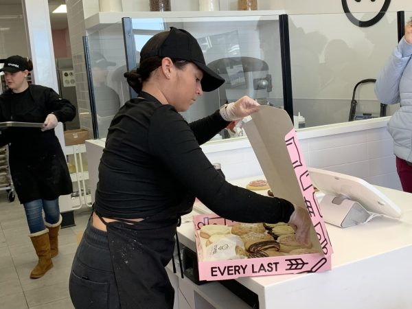 Crumbl baker, Ariana Cantu, packs a 12-pack box of cookies for a customer Friday. The cookie store opens at 8 a.m. Monday through Saturday, closing at 10 p.m. from Monday to Thursday and at midnight for the rest of each week. (Rachel Cormier | Northern Star)