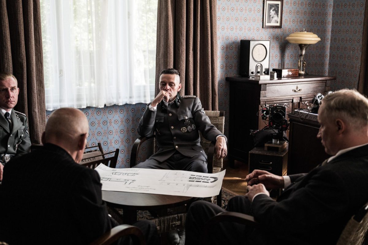 Rudolf Höss (Christian Friedel) sits at a table looking at a plan for a new furnace. Höss is the patriarch of the main family in the 2023 film The Zone of Interest. (Agata Grzybowska | A24)