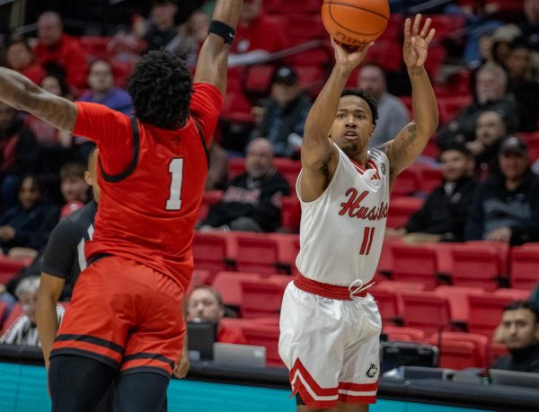 Junior guard David Coit (11) shoots a three-pointer over Ball State junior guard Jalin Anderson (1) on Feb. 20. Coit led the Huskies in scoring with 27 points in a 75-72 upset win over the University of Toledo on Tuesday. (Tim Dodge | Northern Star)