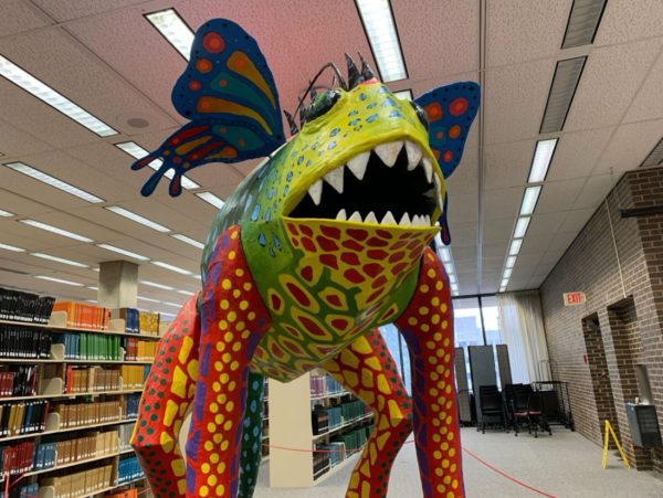 The Alebrije Mykel, a toad, butterfly and alien chimera stands above library-goers on the first floor of Founders Memorial Library. Twenty-two pieces from the “Alebrijes: Creatures of a Dream World” will be showcased in the Founders Memorial Library until Nov. 8. (Rachel Cormier | Northern Star)