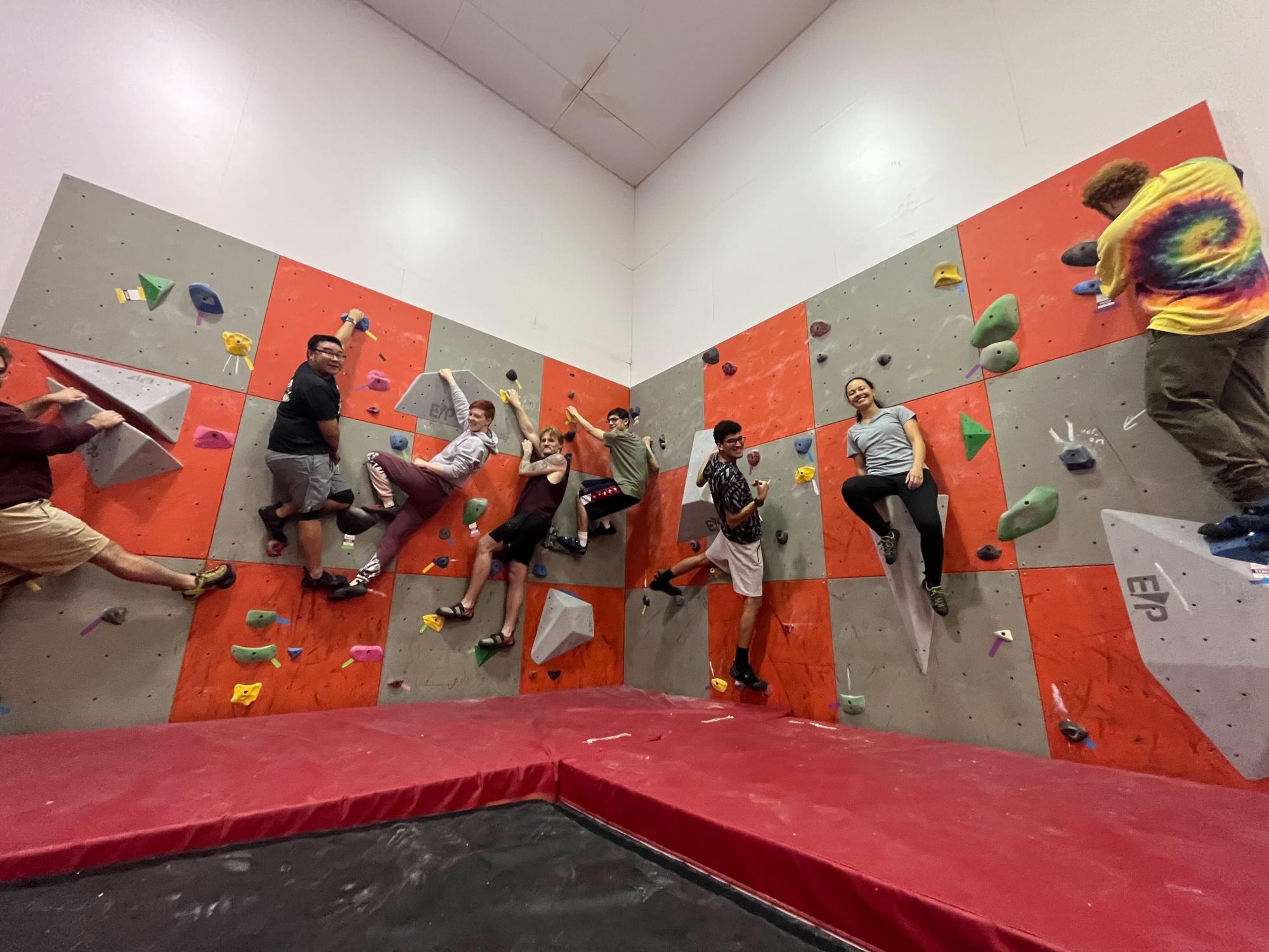 Eight students smile while hanging onto a rock climbing wall. NIUs Climbing Club has been an official sports club since 2022 and is open to all students. (Sofia Didenko | Northern Star)