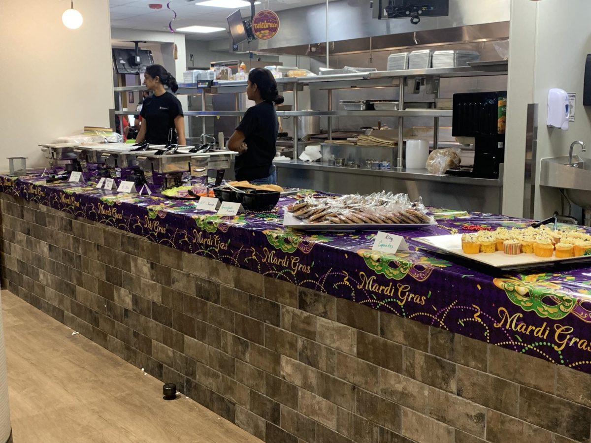 Multiple different foods sit on a counter with a Mardi Gras table cloth. NIU Dining Services put on a Mardi Gras Fat Tuesday lunch. (Victoria Wakeford | Northern Star)