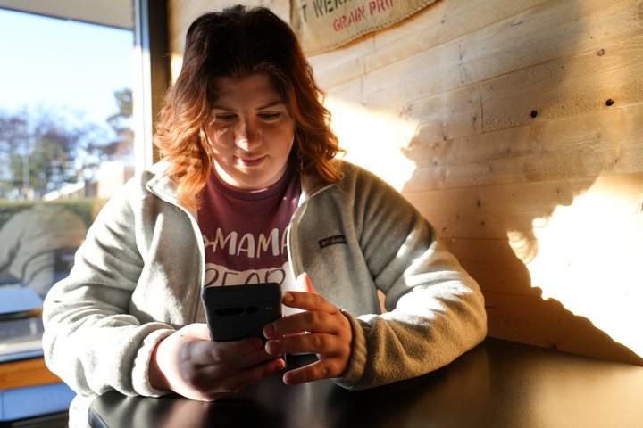 Rebecca Franzen sits on her phone, illuminated by morning light. Coming to Cast Iron Coffee is a part of her morning routine because she “likes the quiet atmosphere and minimal distractions,” Franzen said. (Anna Scanlan | Northern Star)