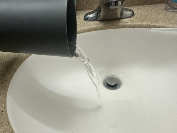 A gray cup pours water into a sink. DeKalb should not have won the award for Best Tasting Water on Jan 26. (Olivia Zapf| Northern Star)