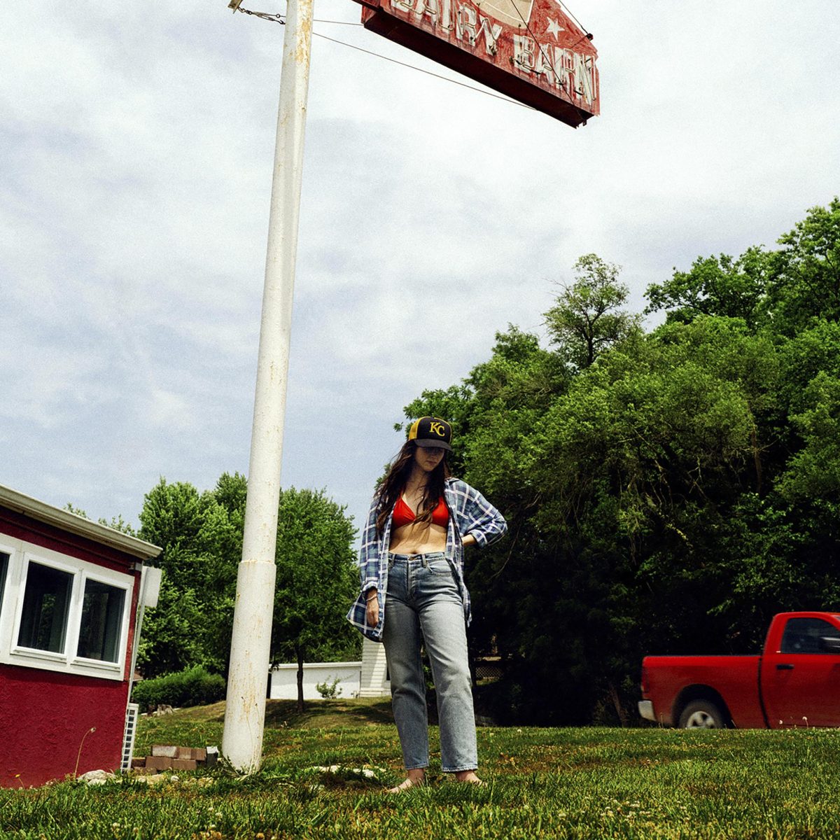 A woman stands beside an old neon sign with some trees and a red pickup in the background. This image is the cover to Waxahatchees newest album Tigers Blood, one of three major indie-folk albums to release this week. (ANTI Records via AP)