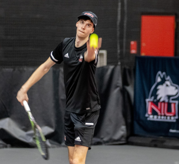 Freshman Saul Berdullas throws up a serve against Omaha on March 2. Berdullas was the lone Huskie to win a singles match in a  5-2 loss to Western Michigan University. (Norther Star File Photo)