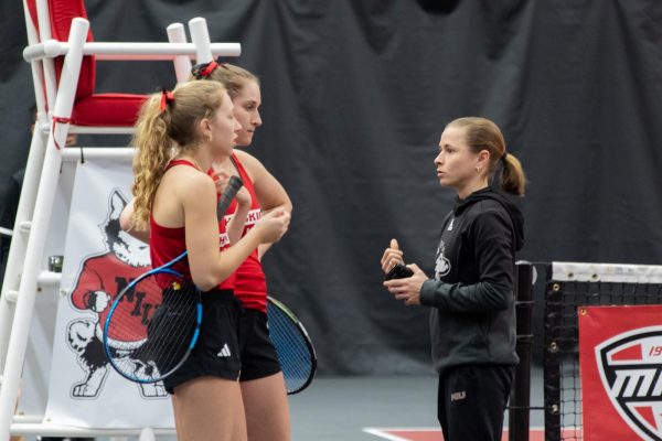 NIU sophomore Jenna Horne and junior Reagan Welch talk to assistant coach Ksenija Tihomirova while switching sides on the court. Horne and Welch won their doubles match against Eastern Illinois University 6-2. (Katie Follmer | Northern Star)