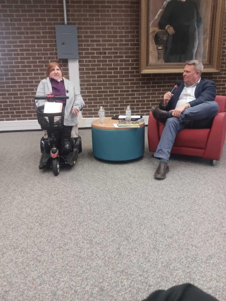 Author Melissa Blake (left) sits with Fred Barnhart, dean of NIU libraries, who has a microphone in his hand. Blake came to NIU on Thursday to discuss her new book, “Beautiful People: My Thirteen Truths About Disabilities, which interrogates disability and the way disability impacts peoples lives. (Caleb Johnson | Northern Star)