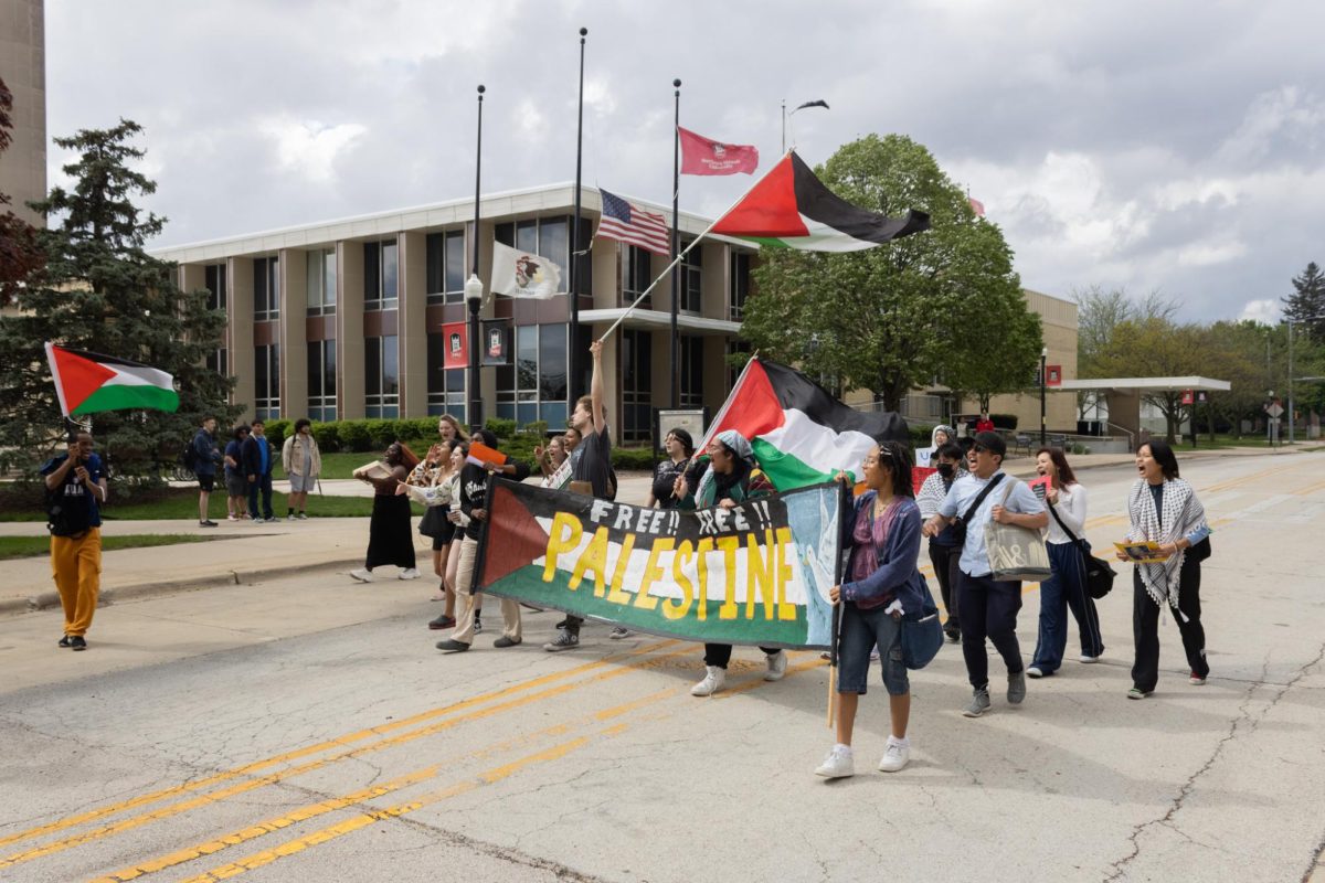 NIU student protesters march down the permanently closed Normal Road near the MLK Commons. Palestine protesters marched through NIU’s campus on Monday. (Sean Reed | Northern Star)
