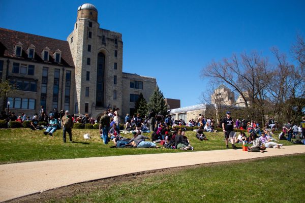 People sit on the grass during the eclipse on Monday behind Lowden Hall. At this eclipse event, students could watch the sky, learn about the eclipse or hang out with friends. (Totus Tuus Keely | Northern Star)
