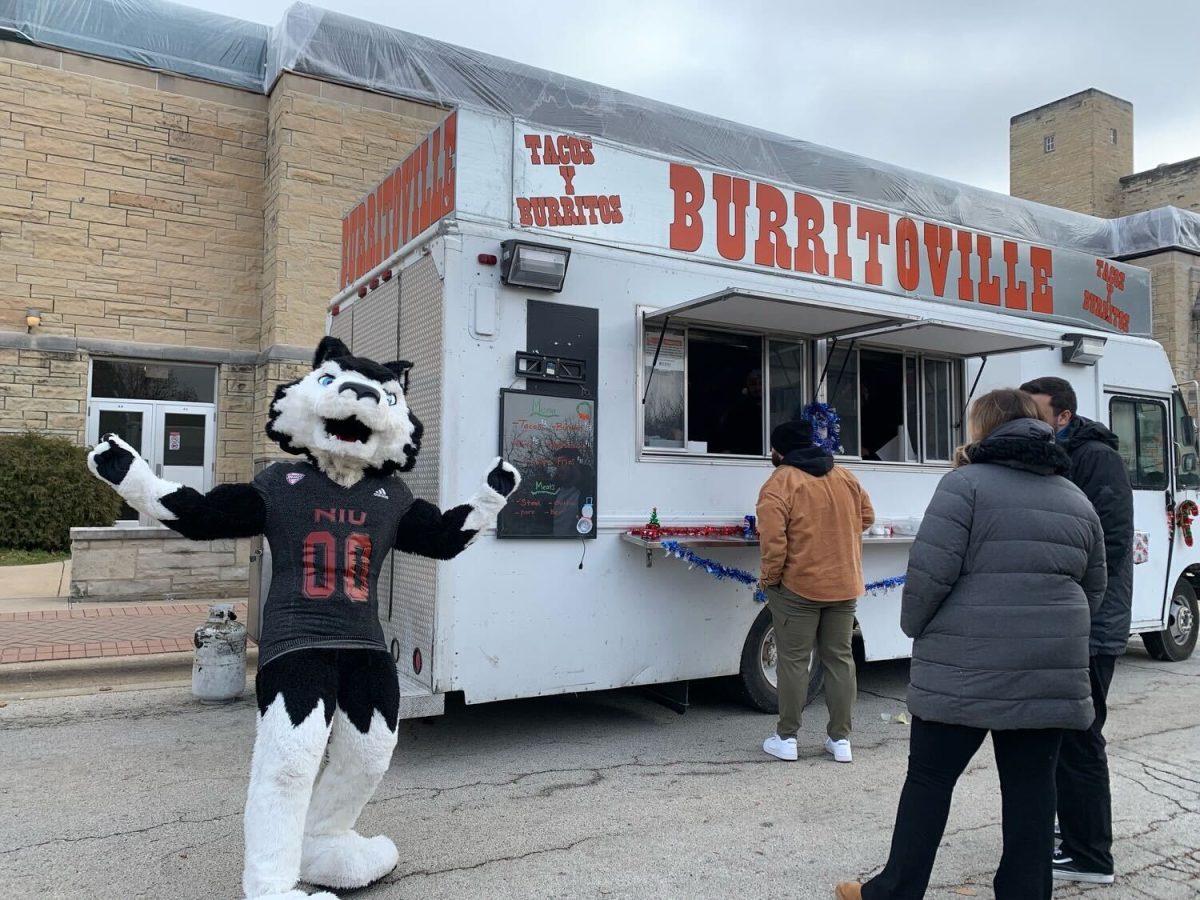 Victor E. Huskie poses in front of the Burritoville food truck during the fall semester. Food Truck Wednesday is starting back up from 11 a.m. to 2 p.m. Wednesday with eight new food trucks. (Rachel Cormier | Northern Star)