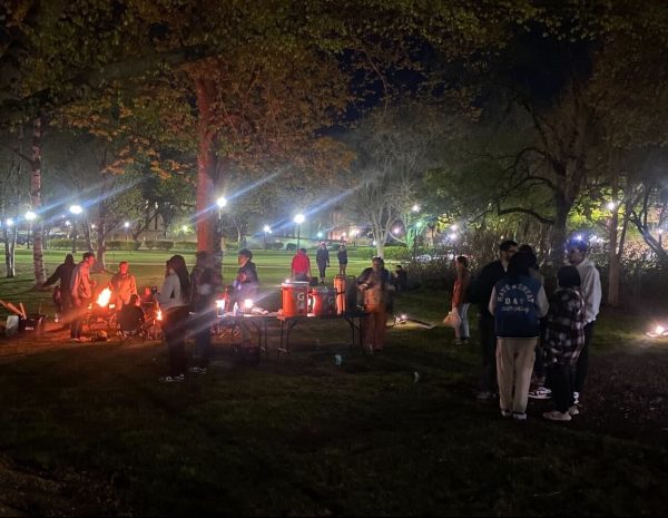 Students crowd around a campfire at the East Lagoon. On Tuesday the Recreation Center hosted an outdoor celebration for students with kayaking, canoeing and s’mores. ( Zahra Yousif | Northern Star) 
