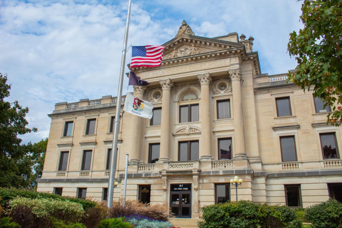 The DeKalb County Courthouse, 133 W State St. sits under a blue sky with the American flag and the Illinois flag in front of it. Saturday the Walk to End Child Abuse will walk from Sycamore High School to the court house. (Northern Star file photo)