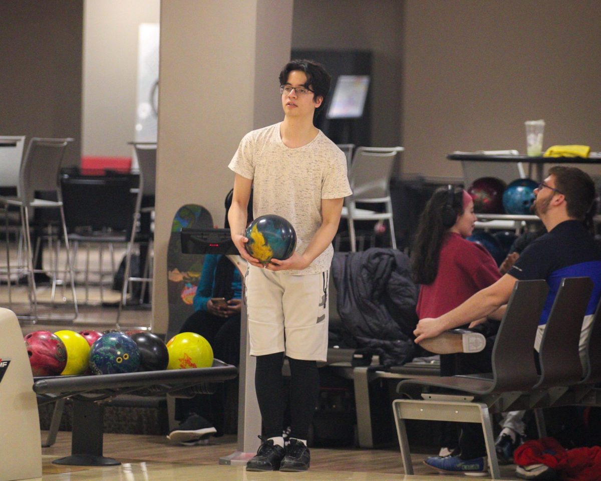 Adam Smith, a junior mechanical engineering major, looks down at the pins getting ready to deliver the ball down the lane. The Graduate school of NIU hosted a Bowling and Billiards event for students on Monday. (Tim Dodge | Northern Star)