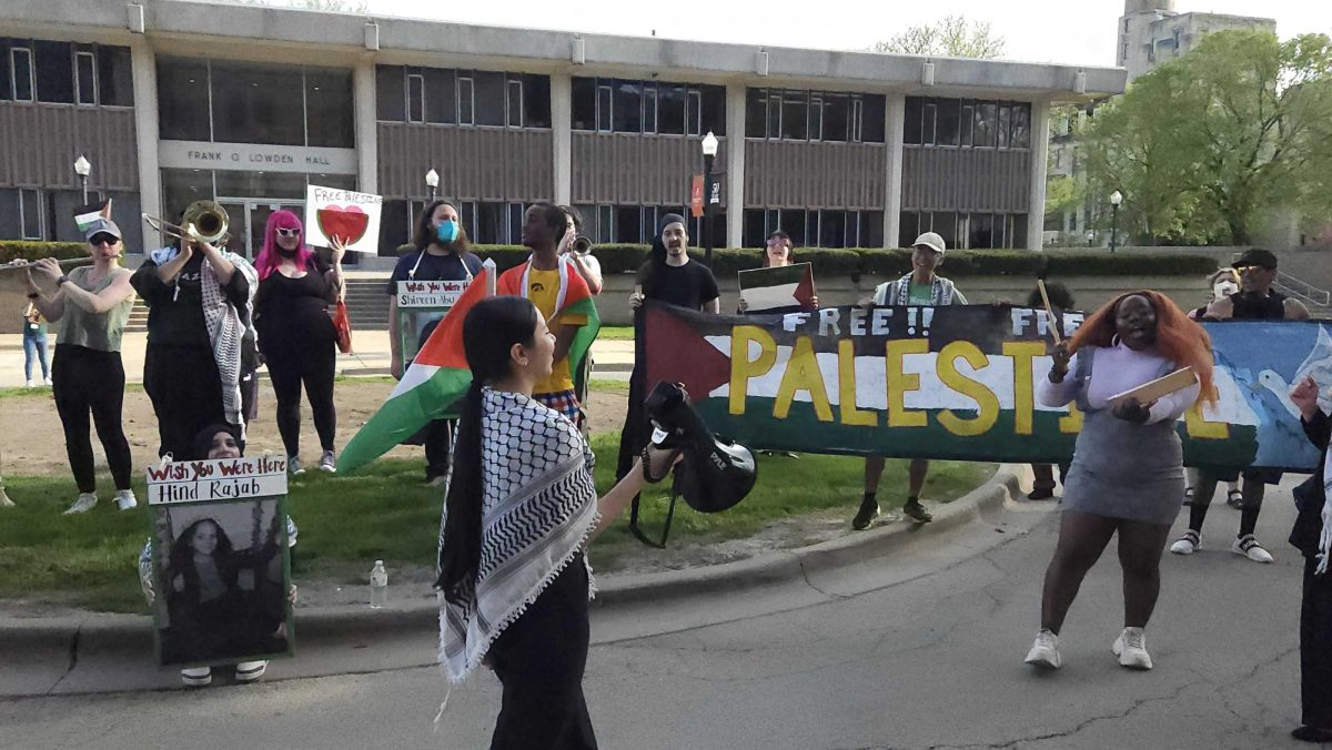 A group of protestors hold signs and chant. Students for Justice in Palestine led a protest through NIUs campus to Altgeld Hall. (Joseph Howerton | Northern Star)