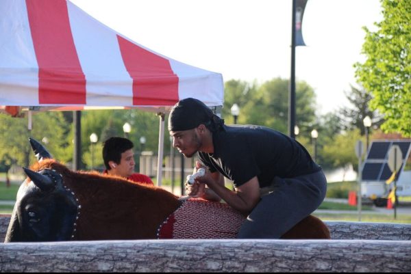 Devante Lee, a first-year computer science major, rides the mechanical bull during the CAB Carnival event Friday. In addition to the mechanical bull, the carnival also consisted of outdoor games, rock climbing and food trucks. (Katherine Follmer | Northern Star)