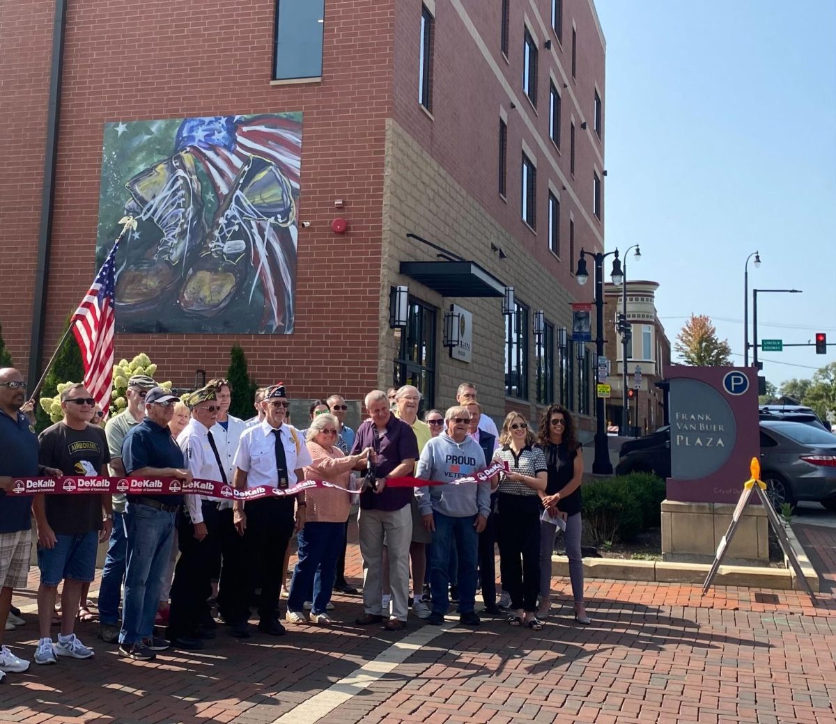 DeKalb Mayor Cohen Barnes cuts a ribbon at the DeKalb veterans memorial dedication Thursday. The mural is located on the north wall of the Plaza DeKalb building. (Brynn Krug | Northern Star)