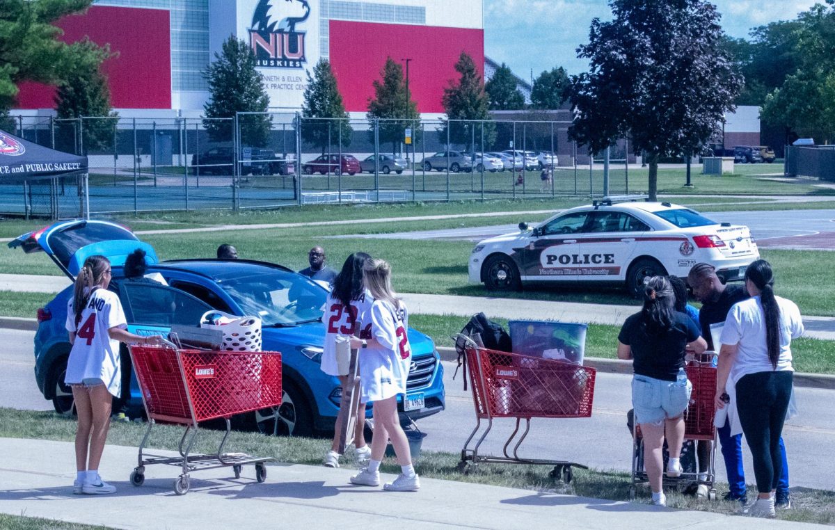 Students and parents unload cars and fill carts with items along the curb of Stevenson Hall. NIU fraternities and sororities volunteered to help new students have a smooth transition into the dorms Wednesday afternoon. (Ryanne Sandifer | Northern Star)