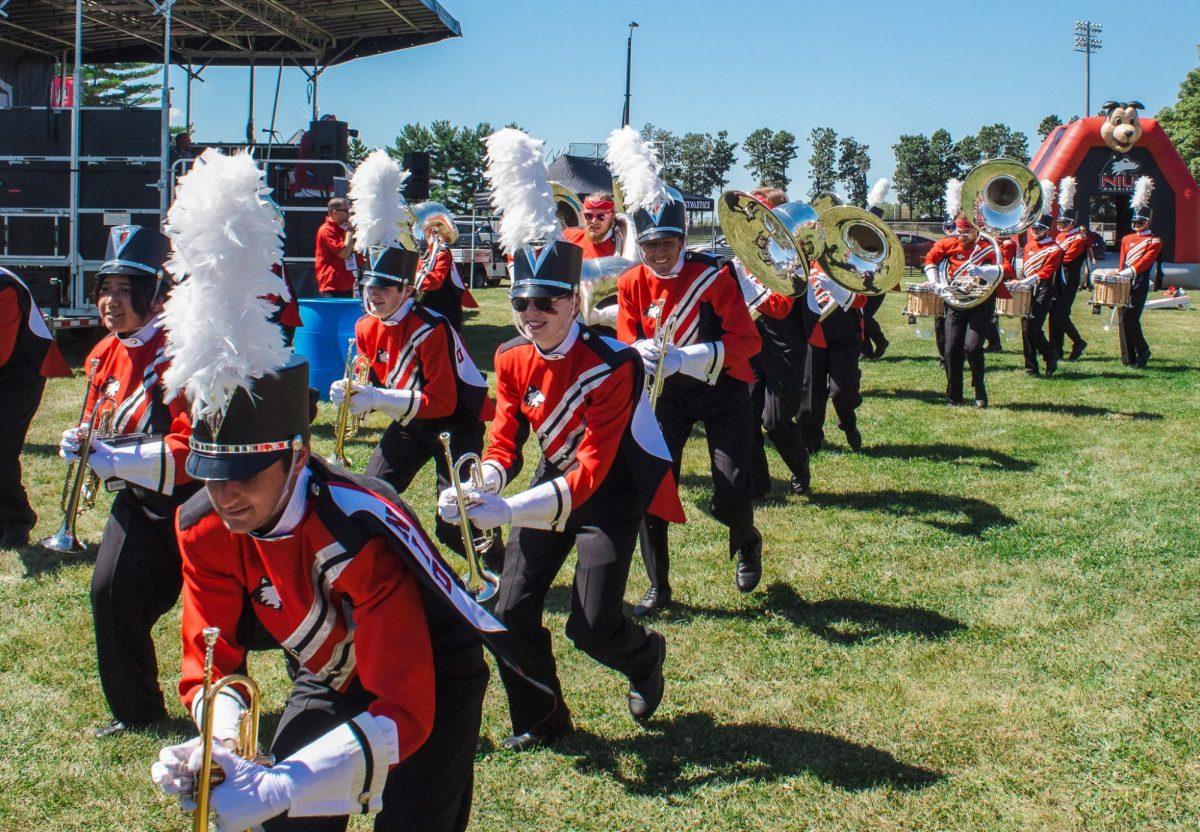 The Pride of the Midwest Marching band marches through the tailgate yard before the Aug. 21 football game with Western Illinois University. The marching band's presence is critical to the atmosphere of any football game, Opinion Columnist Will Thiel argues. (Totus Tuus Keely | Northern Star)