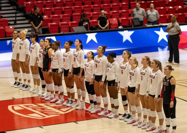 NIU volleyball players stand as they look up to the American flag in the Convocation Center during the National Anthem on Friday during their match against Western Illinois University. The Huskies’ next match is against the University of Valparaiso on Sept. 5 in St. Paul, Minnesota. (Tim Dodge | Northern Star) 
