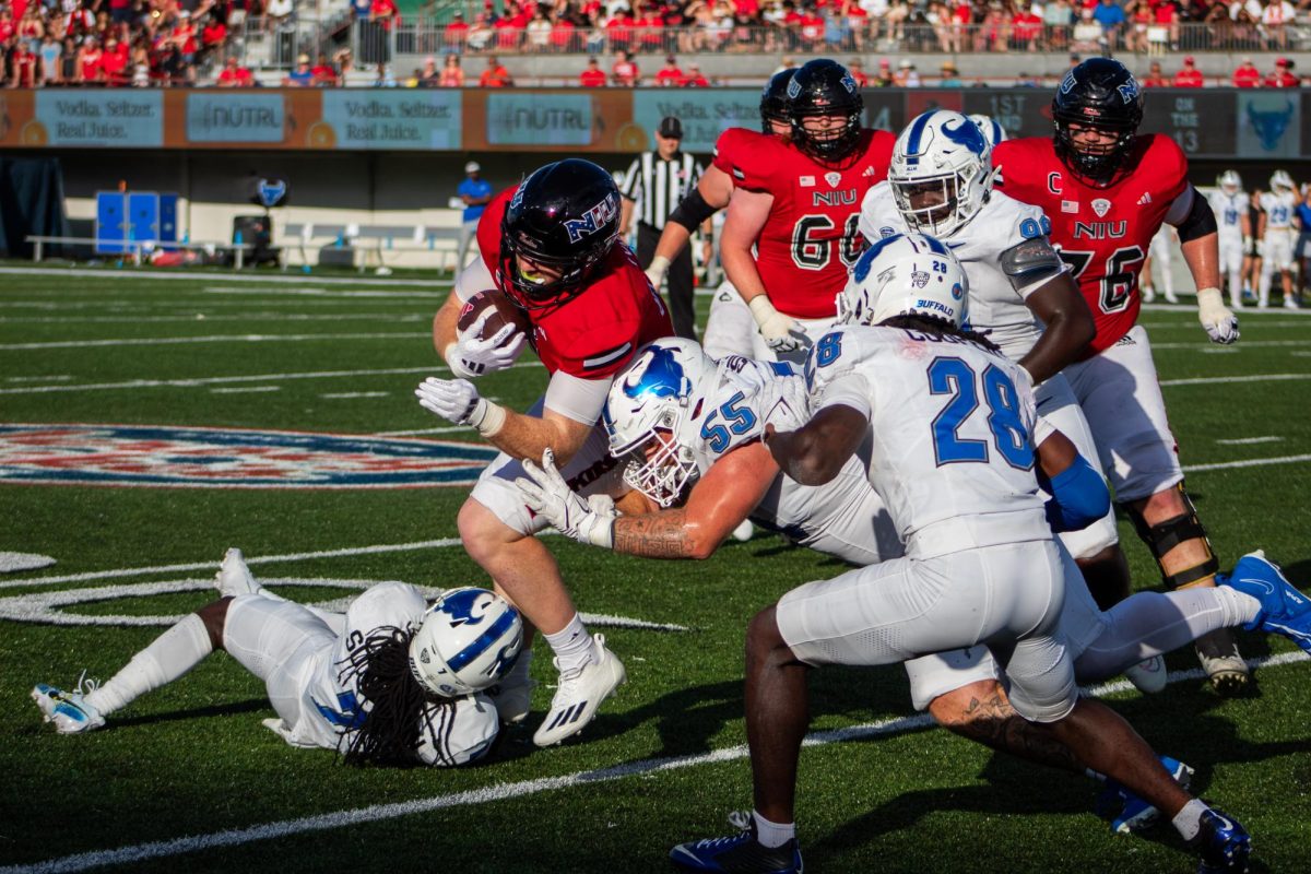 NIU redshirt junior running back Justin Lynch is tackled behind the line of scrimmage by University at Buffalo redshirt fifth-year nickel Solomon Brown (7) and junior defensive tackle Tristan Souza (55) in the third quarter of Saturday's 23-20 overtime loss to Buffalo at Huskie Stadium. Lynch was one of nine NIU players to record a catch in the game, finishing with two receptions for 3 yards. (Totus Tuus Keely | Northern Star) 